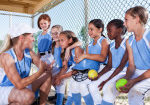 Softball team:  Coach (40s) with girls (7-10 years) in dugout.